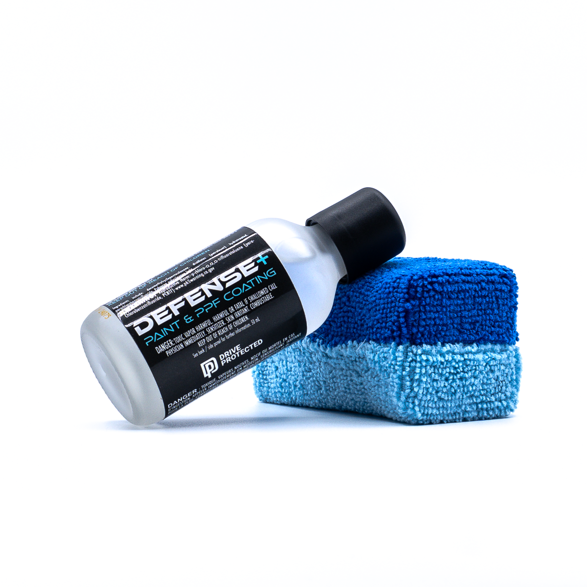 Bottle of Defense+ Paint & PPF Coating by Drive Protected leaning against an applicator pad