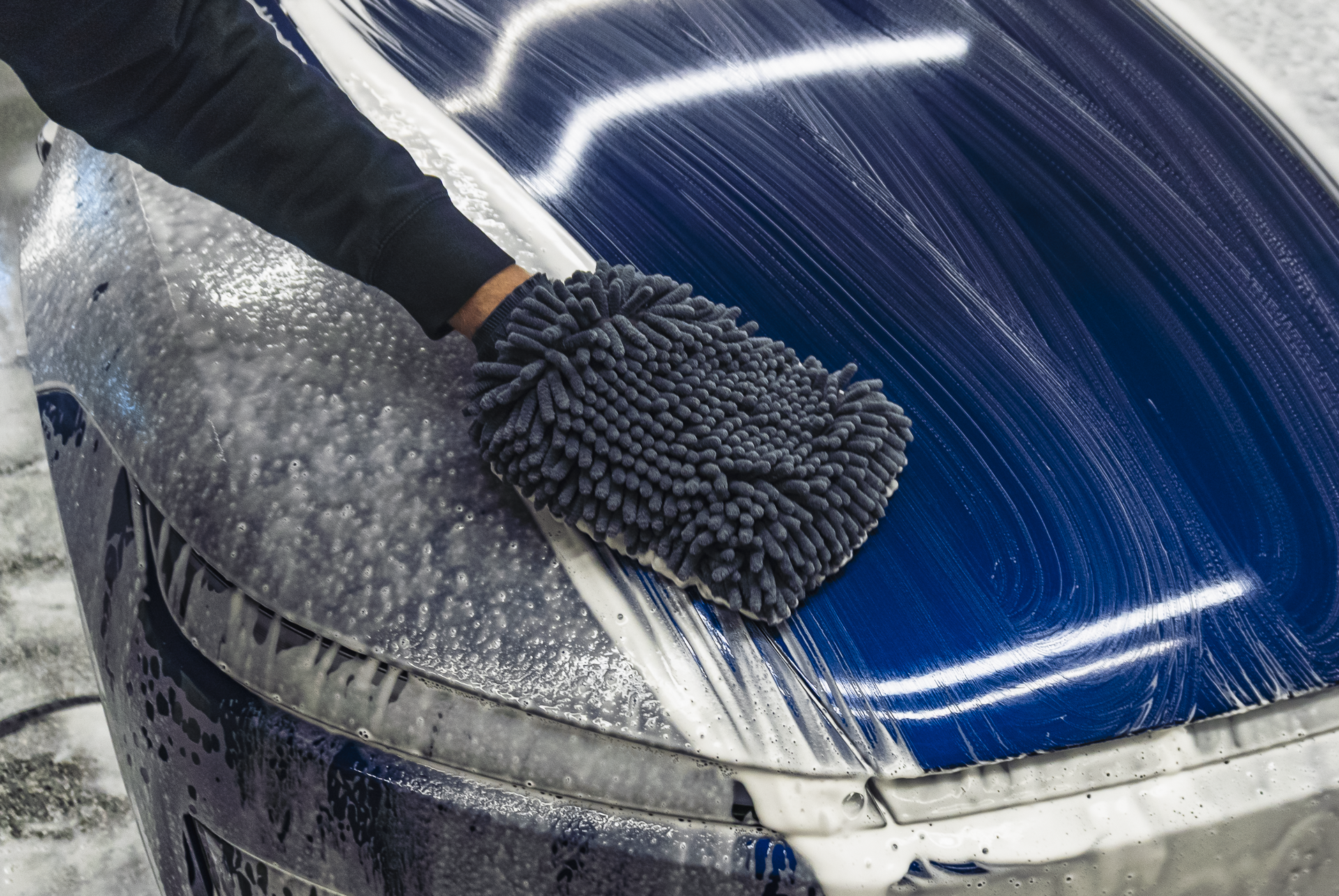 Person cleaning a car's hood with a microfiber towel