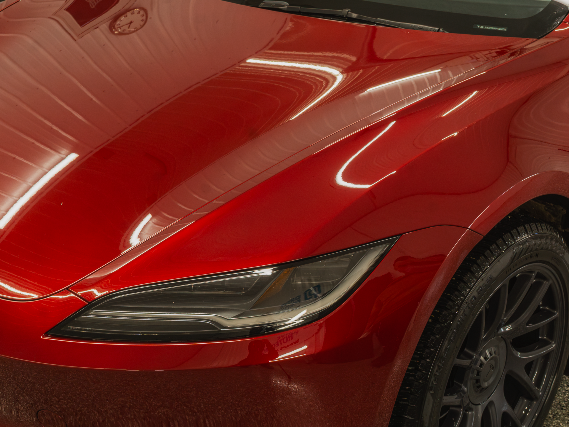 Close-up of a red car's front headlight and grille