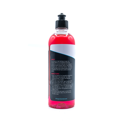 Bottle of car care product with red liquid and black label on a white background