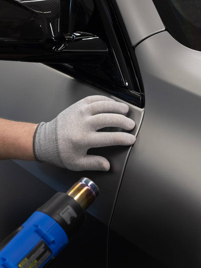 Person applying car wrap to a vehicle with a heat gun