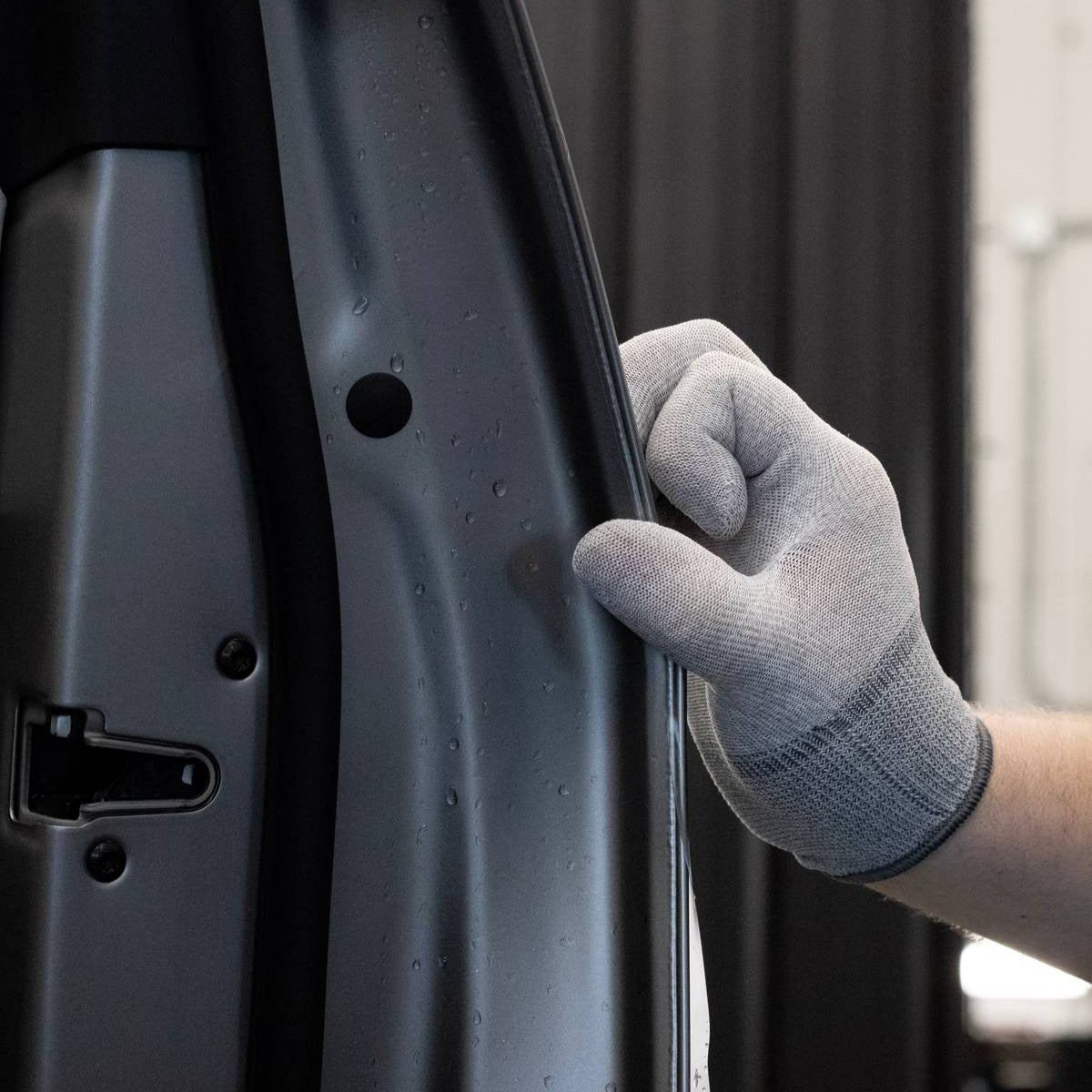 Person wearing a gray warp glove finishing a ppf door panel.