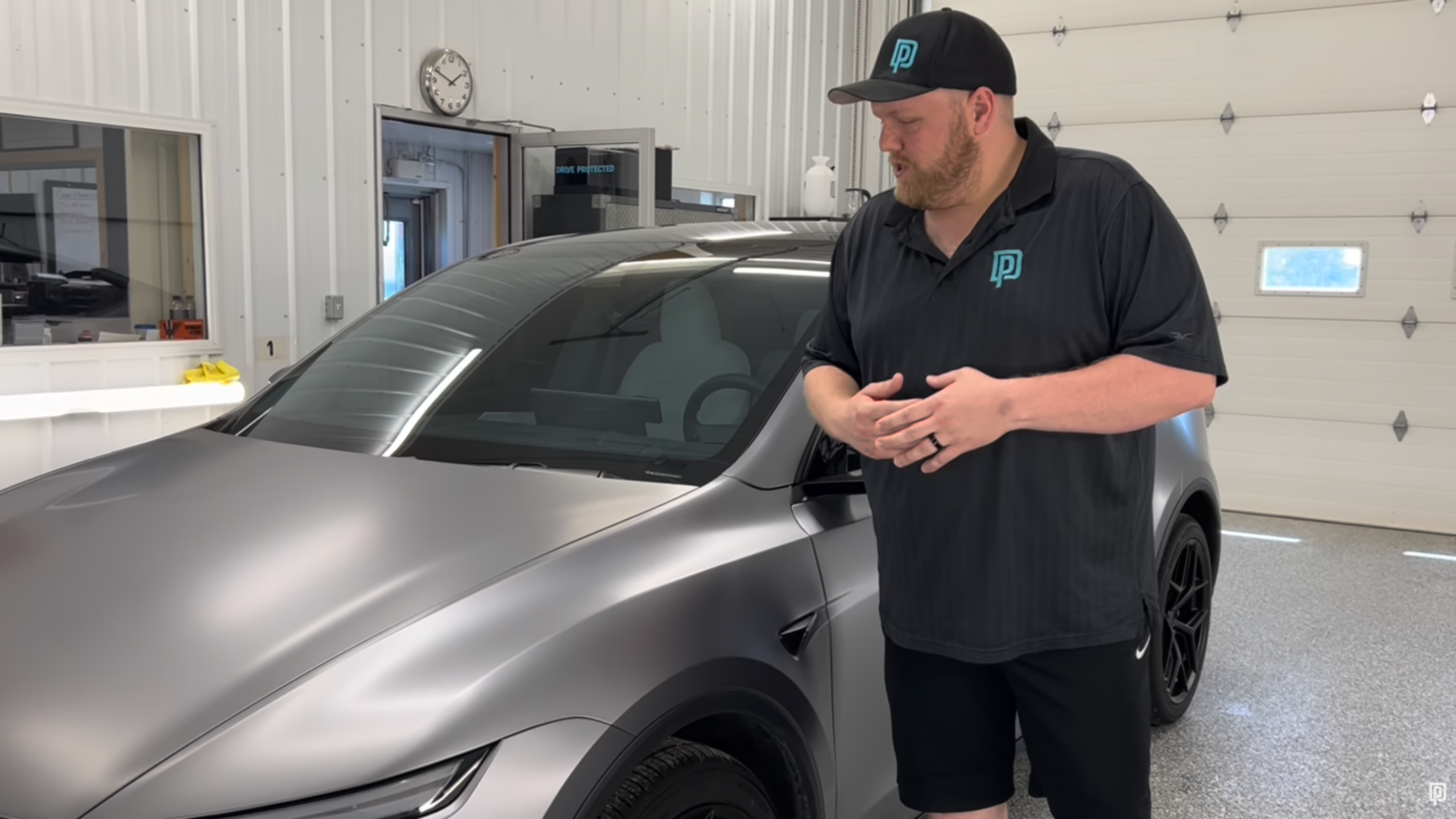 Man standing next to a silver car in a garage