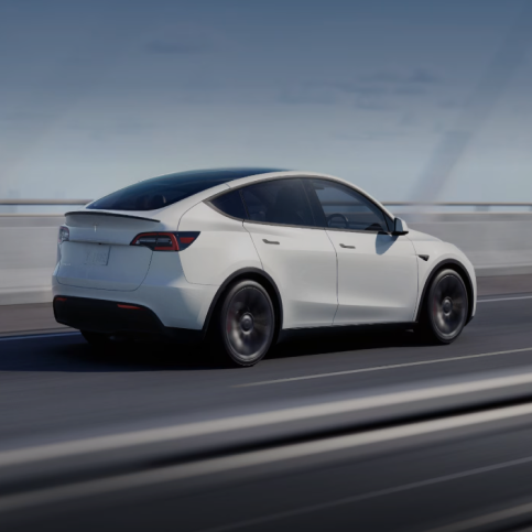 White Tesla Model Y driving on a road with a blurred background