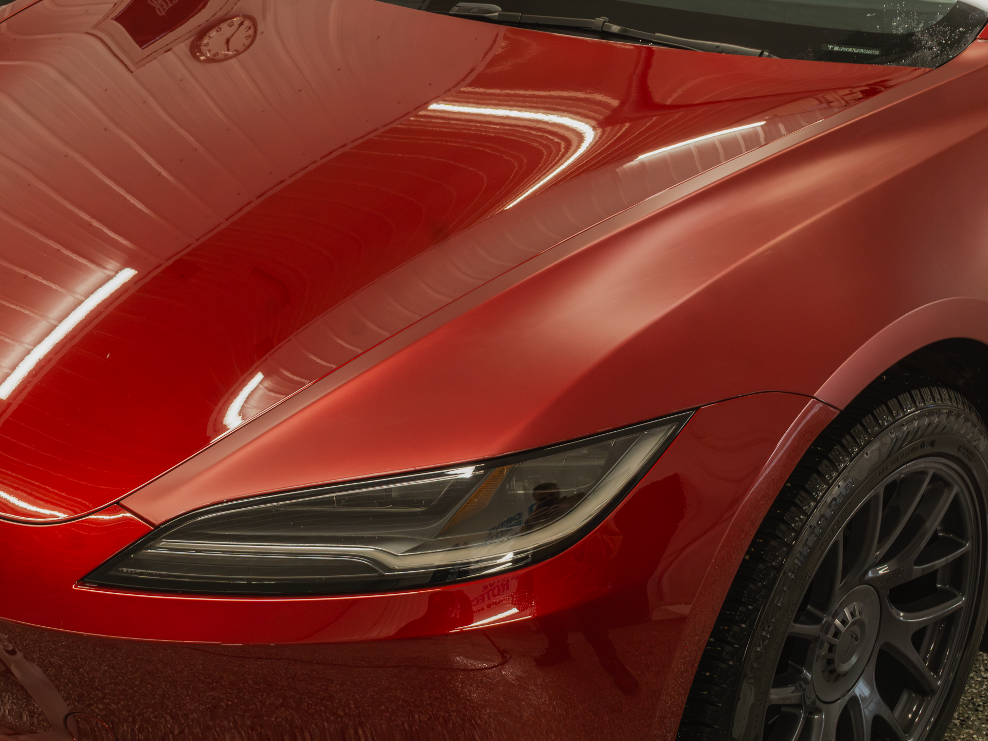 Close-up of a red car's front headlight and hood